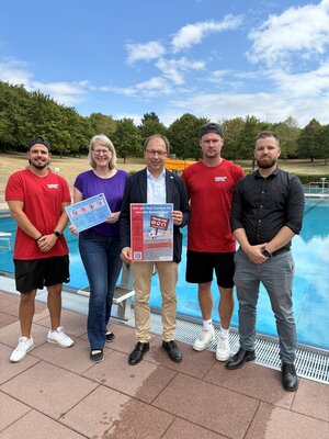 Bild vergr&ouml;&szlig;ern: Vier M&auml;nner und eine Frau stehen vor dem Schwimmbecken. Sie machen auf eine Kampagne zum Schutz der Besucher aufmerksam.